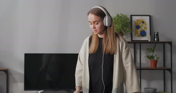 Woman Is Dancing and Singing During Hoovering at Home Listening To Music By Headphones Medium alt