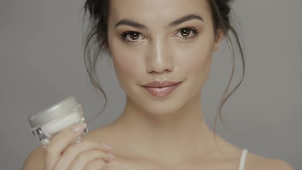 Pretty Girl Holding Cream and Looking To Camera alt