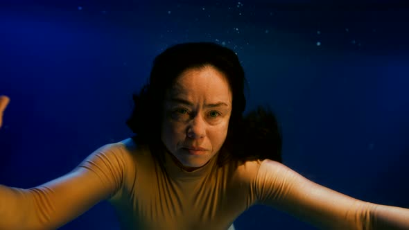 Portrait of Brunette Woman Swimming Underwater Closeup View of Face and Swaying Hair Slow Motion alt