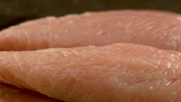 Close up of raw turkey fillet meat on the table rotates. Preparing delicious turkey meat dishes alt