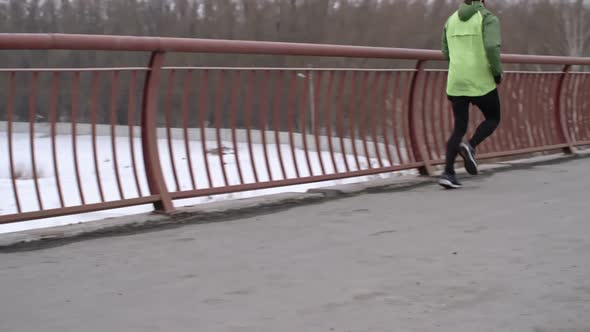 Man Practicing Winter Running on Bridge alt