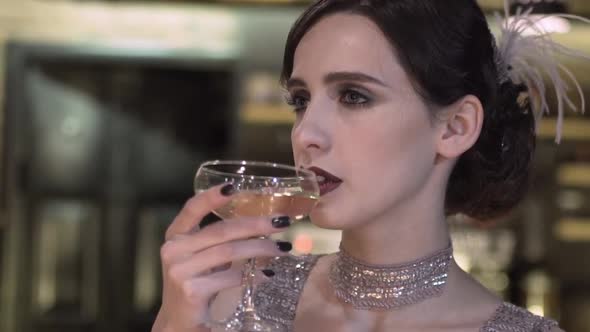 Closeup Portrait of a Young Attractive Woman in a 1920s Style Drink Wine or Champagne at the Bar alt