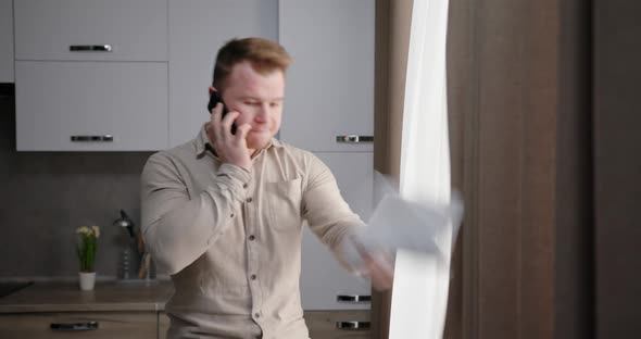 Angry Man Speaking on Smartphone in Kitchen