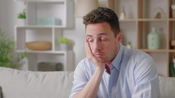 Sad Bored Man Lean Head on Hand Thinking Seated on Sofa at Home Alone Lost Deep in Thoughts Feeling alt