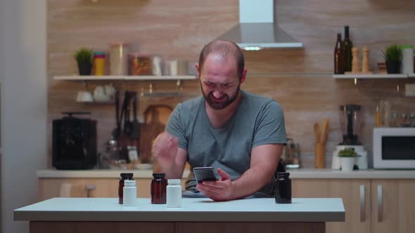 Man with Headache Holding Pills Bottle alt