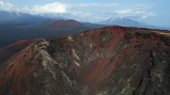 red mountain with a view of snow volcanoes