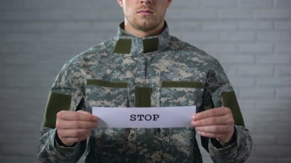 Stop Word Written on Sign in Hands of Male Soldier, End of War Conflict, Protest alt