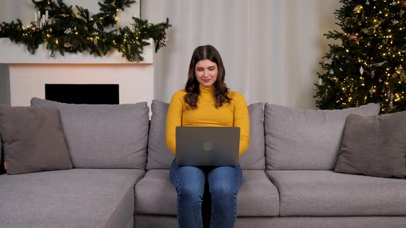 Woman Uses Laptop Online Chatting with Friends on Background Christmas Tree alt