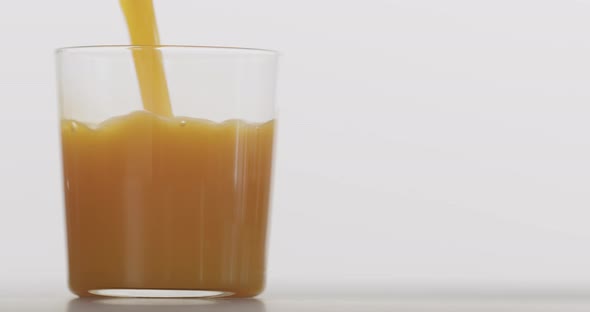 Slow Motion Sea Buckthorn Juice Pour Into Thin Tumbler Glass with White Background alt