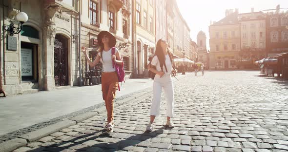 Lady Tourists with Backpacks Walking in City