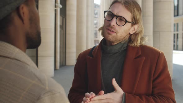 Handsome Businessman Speaking with Colleague Outdoors in City alt