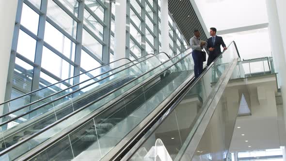 Young business people on an escalator in a modern building alt