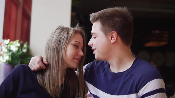 Young Couple Sitting at the Table in Cafe Embracing Each Other alt