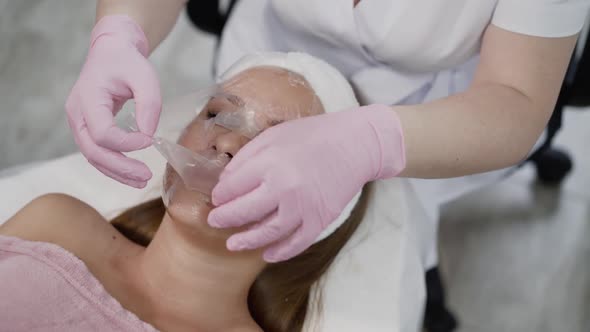 Beautician's Hands Put a Membrane on Female Face with Anesthetic Cream in Clinic alt