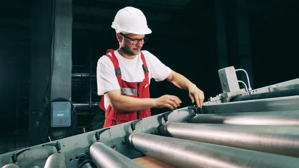 Male Engineer Is Working with the Rolling Conveyor alt