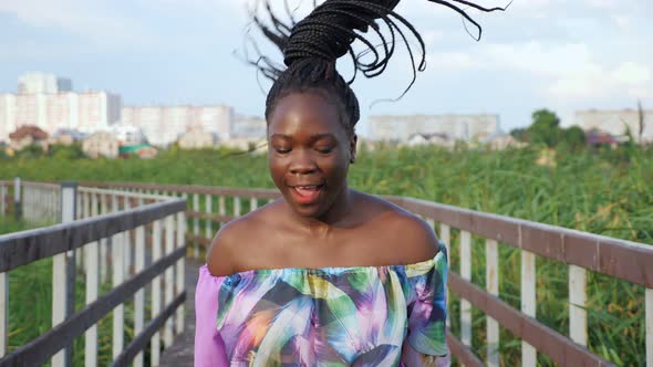 AfricanAmerican Lady in Blouse Shakes Long Hair on Bridge alt