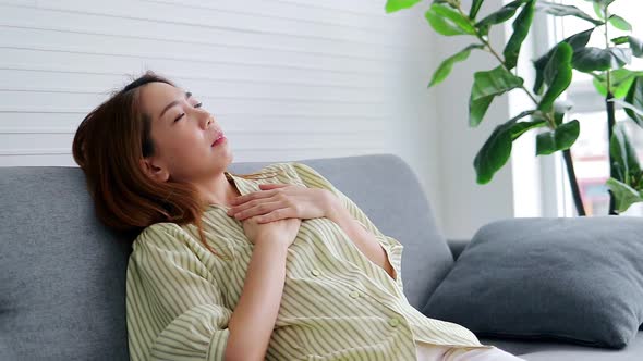 Asian woman lying on the sofa in the house She had a sharp pain in her heart alt