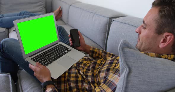 Young man using laptop in living room at home 4k