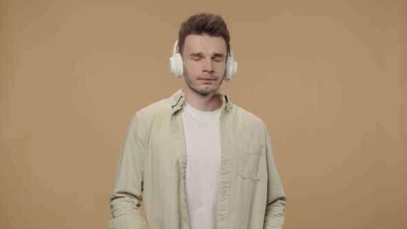 Portrait of Stylish Guy Enjoying Music in Big Wireless White Headphones alt