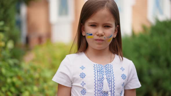 Rack Focus From Face of Pretty Ukrainian Girl in Embroidered Shirt to Raised Hand with Flag Colors alt