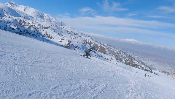 Man Snowboarder on Snowboard Running Down the Slope in Ski Resort