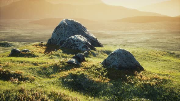 Meadow with Huge Stones Among the Grass on the Hillside at Sunset alt