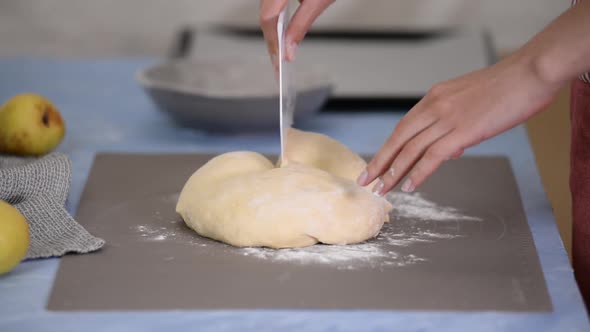 A woman's hands cut the dough for baking. Baker kneading dough in a bakery.