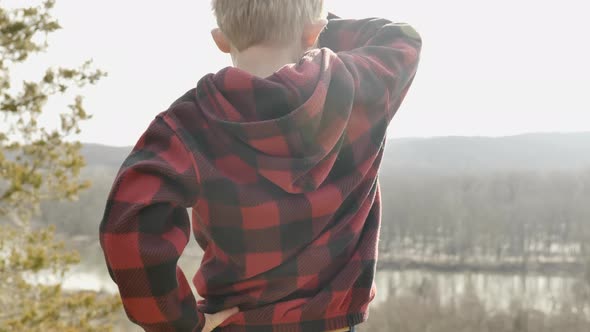 Toddler looking out over valley during bright sunny day. Pan tilt up alt