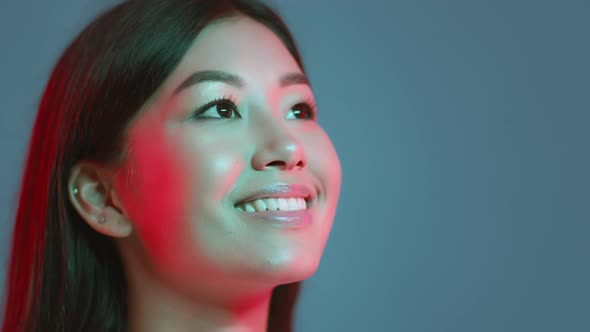 Young Pretty Asian Woman Looking at Free Space and Sincerely Smiling Expressing Inspiration Blue alt
