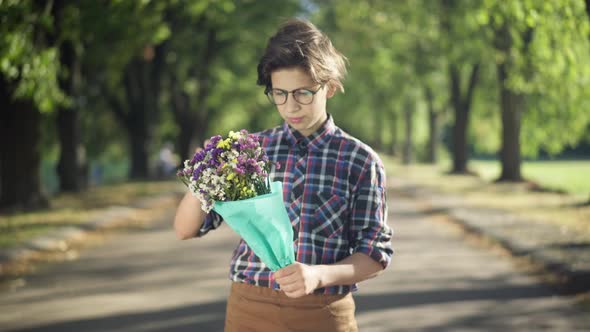 Portrait of Teenage Boy with Bouquet of Flowers Standing in Sunbeam in