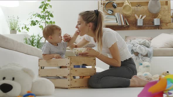 Happy and smiling mom with the beautiful baby child inside a wooden box