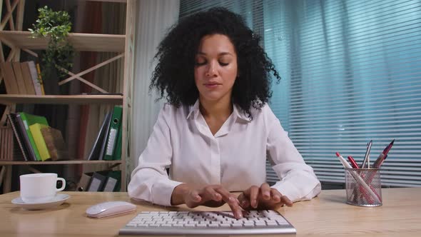 Portrait of African American Woman Typing on Computer Keyboard Looking Directly at Monitor alt