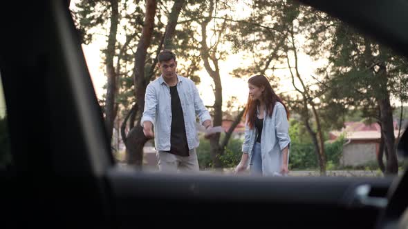 Positive Man and Woman with Paper Maps Talking Looking at Car at Front alt
