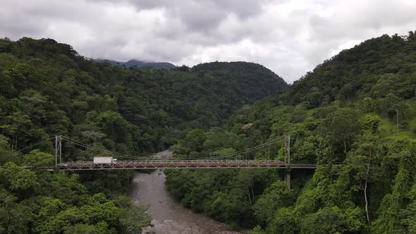 Drone slowly approaching a run-down steel bridge surrounded by thick rainforest in the middle of now alt
