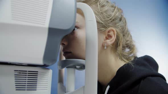 A Young Girl at an Ophthalmologist's Office Checks Her Eyesight with a Professional Device alt