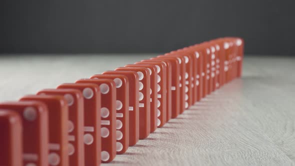 Domino Effect - a Series of Red Dominoes Falling Down the Chain on Wooden Table alt