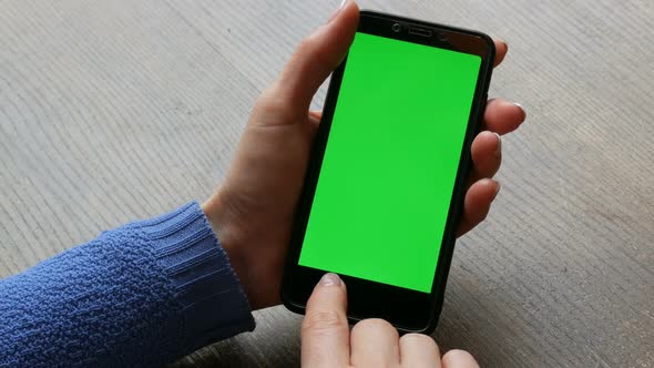Chroma Key or Green Screen on a Black Smartphone in Female Hands with a Wellgroomed Manicure on a alt