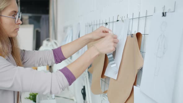 Pensive Dressmaker Designing New Garments and Choosing Fabric Working Indoors in Studio alt