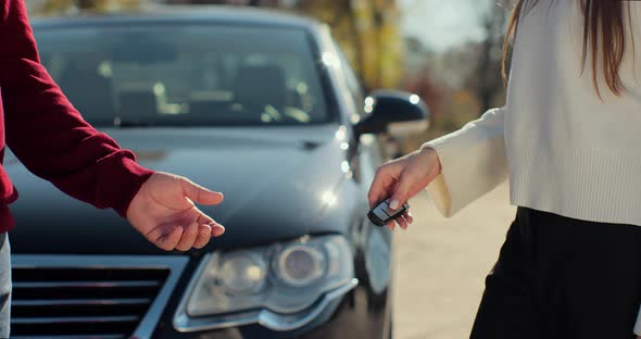 Woman Hand Gives a Car Keys to Man Hand in the Car Dealership Close Up alt