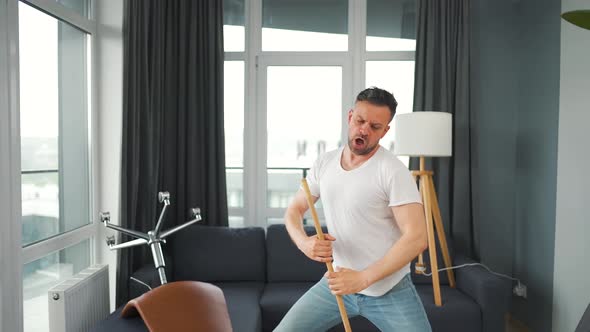 Man Cleaning the House and Having Fun Dancing and Singing with a Broom alt