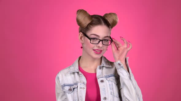 Teenager in Glasses Flirts with a Guy. Pink Background. Slow Motion alt