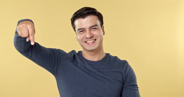 Cheerful smiling Hispanic man pointing hands downwards