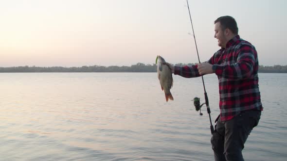 Male Angler Catching Fish Near Cat in Morning