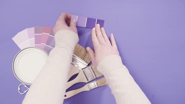 Close up of metal paint can with purple paint and paint swatch. alt