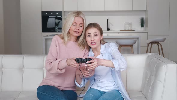 Happy Grown Daughter Teach To Play Video Games on Console While Sitting on Couch in Front of Tv alt