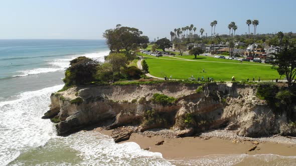 Aerial drone shot of green beach cliffs over the ocean waves crashing on the sandy coast in Santa Ba alt