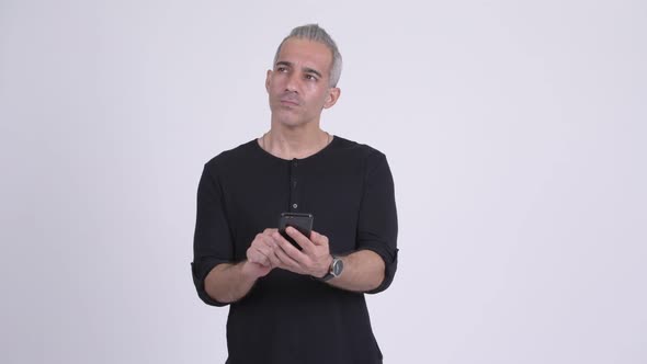 Happy Handsome Persian Man Thinking While Using Phone alt