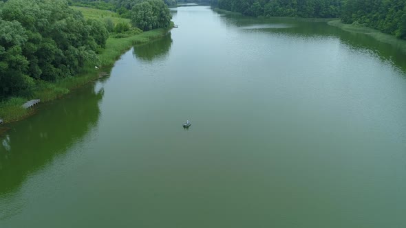 Aerial View Fisherman is Fishing Sitting on an Inflatable Boat in Lake alt