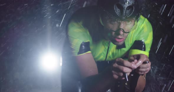 Triathlon Athlete Riding a Professional Racing Bicycle on an Intense Workout in Dark with Rain alt