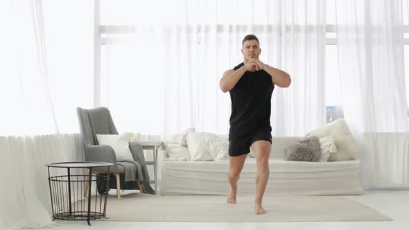 Athletic Young Man Is Doing Lunge Squat Exercise in Jump in Living Room at Home
